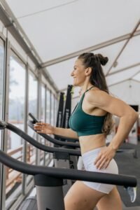 Fit woman jogging on treadmill in an airy gym, focused on health and fitness.